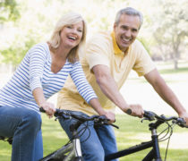 Couple on bikes outdoors smiling Couple on bikes outdoors smiling