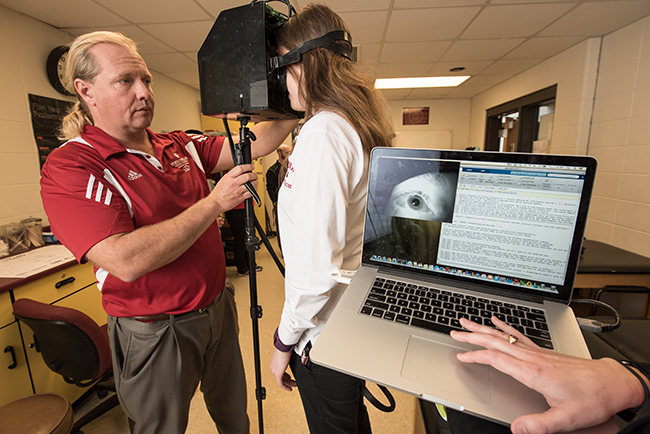 Nicholas Port tests an athlete with the portable concussion device. Photo by John Bailey, directed by Jeff Richardson