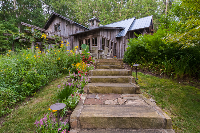 In Kathy and Gary Anderson's garden, the weathered wood of the barn and the stone steps leading to it are softened by flowers and lush greenery. Photo by James Kellar