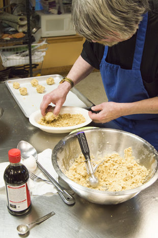 Chef David Davenport coats cookie dough in walnuts after dipping them in the egg white. Photo by Erin Stephenson