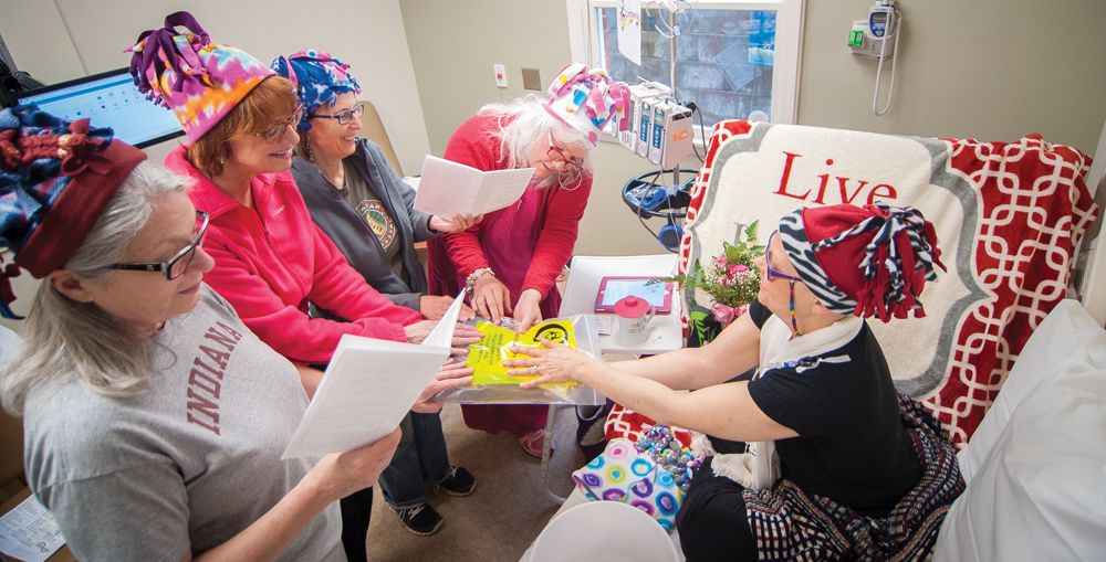 “Chemo-sabe” members (l-r) Linda Summers, Melanie Turner, Christine Missik, and J. Rachel Tucker join Powell in a blessing of her chemotherapy medication prior to the start of treatment.