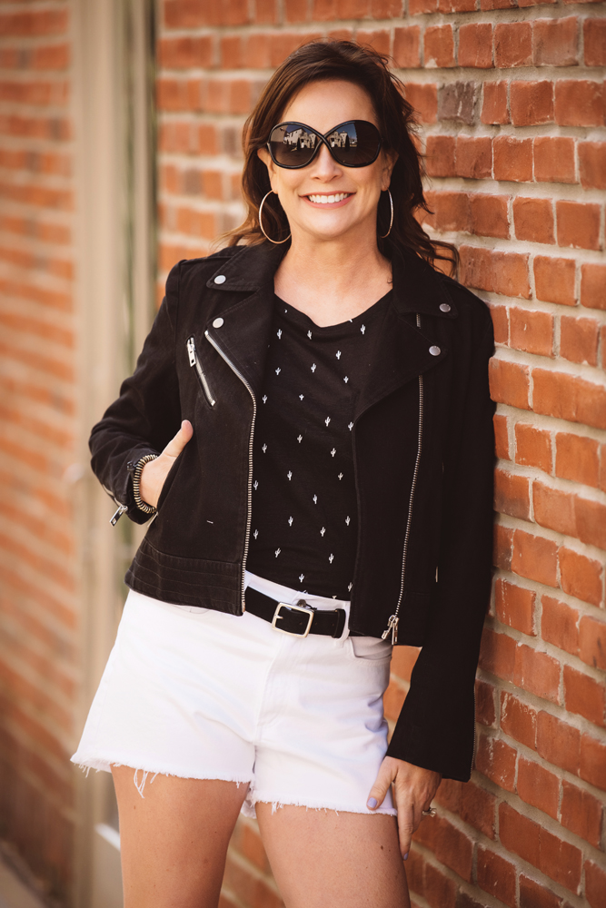 Patty Fox looks sharp in a black denim jacket, white denim shorts, and a black linen T-shirt with a cactus print. Jacket, shorts, and belt by Rag & Bone; T-shirt by Rails; sunglasses by Tom Ford; earrings by Gorjana; and bracelet by Blessings in Disguise.