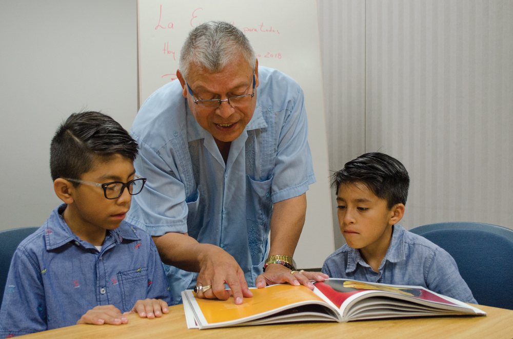Luz Lopez’s sons Cesar Isidro, 10 (left), and Sebastian Isidro, 8, are tutored by Daniel Soto. Photo by Mike Waddell