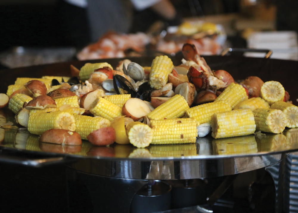 Clam bake of lobster, shrimp, corn, and potatoes alongside a carving station.