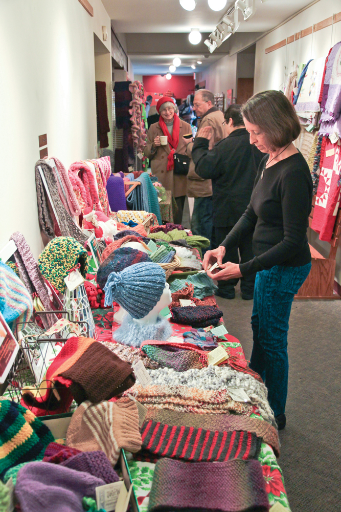 Shoppers look over jewelry, artwork, and knitted hats and scarves at previous Holiday Art Fair and Bazaar events held at the Unitarian Universalist Church of Bloomington.