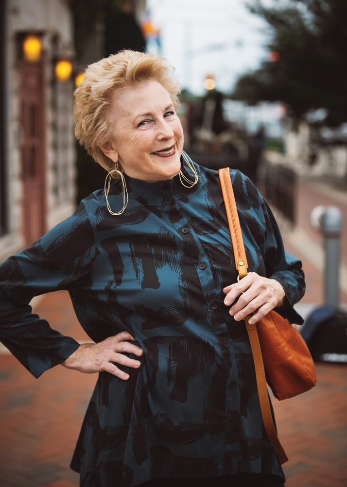 Barbara Weiskopf strikes a pose in a teal and black button-down blouse and mixed-metal hoop earrings. Blouse by Chalet, earrings by Zzan, handbag by Hobo.