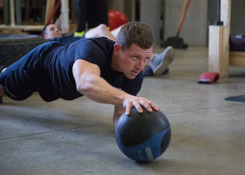 Firefighter engineer Cory Blackwell works out with a medicine ball during a daily fire station workout.
