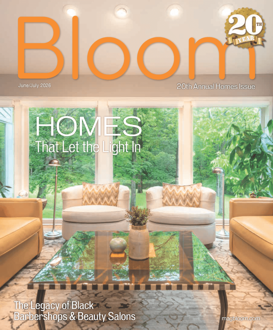 Magazine cover featuring a bright modern living room with large floor-to-ceiling windows overlooking a green wooded landscape, titled “Homes That Let the Light In”